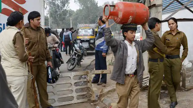 Gurgaon: A boy carries a cylinder on his head as transportation services were disrupted due to Jat community’s agitation for reservation in Gurgaon. (Photo: PTI) 