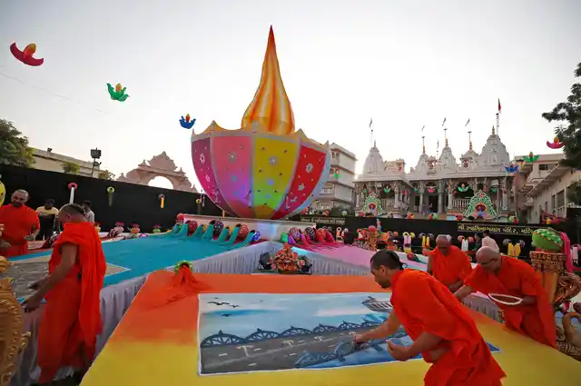 Hindu priests put the finishing touches to a rangoli, or mural made out of coloured powders, at a temple ahead of Diwali festival celebrations in Ahmedabad, India, October 17, 2017. 