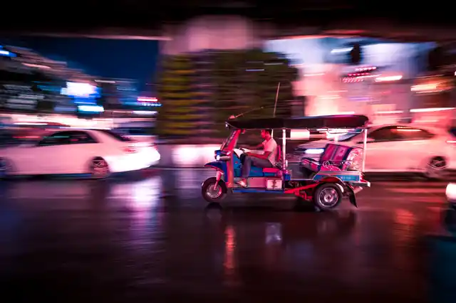 A tuk tuk rushing past traffic as the singal turned green.