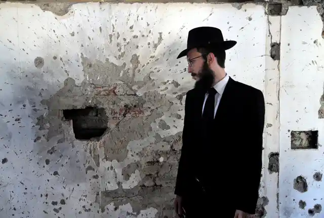 Rabbi Israel Kozlovsky, Director of Chabad House, stands near a partially destroyed wall of the Jewish centre on the eve of the tenth anniversary of the 26/11 Mumbai terror attacks in Mumbai on Sunday, 25 November.