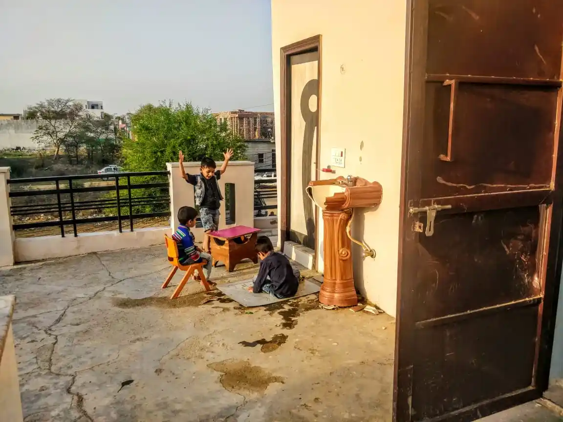 Kids of the house play behind the door that protected Daanishtha from the mob.