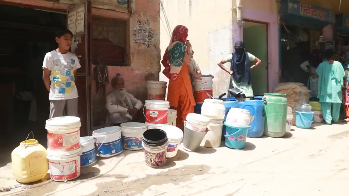 Women wait in the heat to fill water from the water tanker. 
