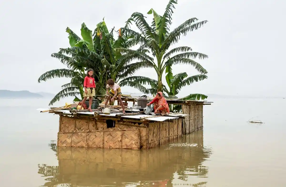 A family marooned on the top of a hut in the flood-hit locality of Panikhaiti in Kamrup district of Assam, on Monday, 15 July 2019. 