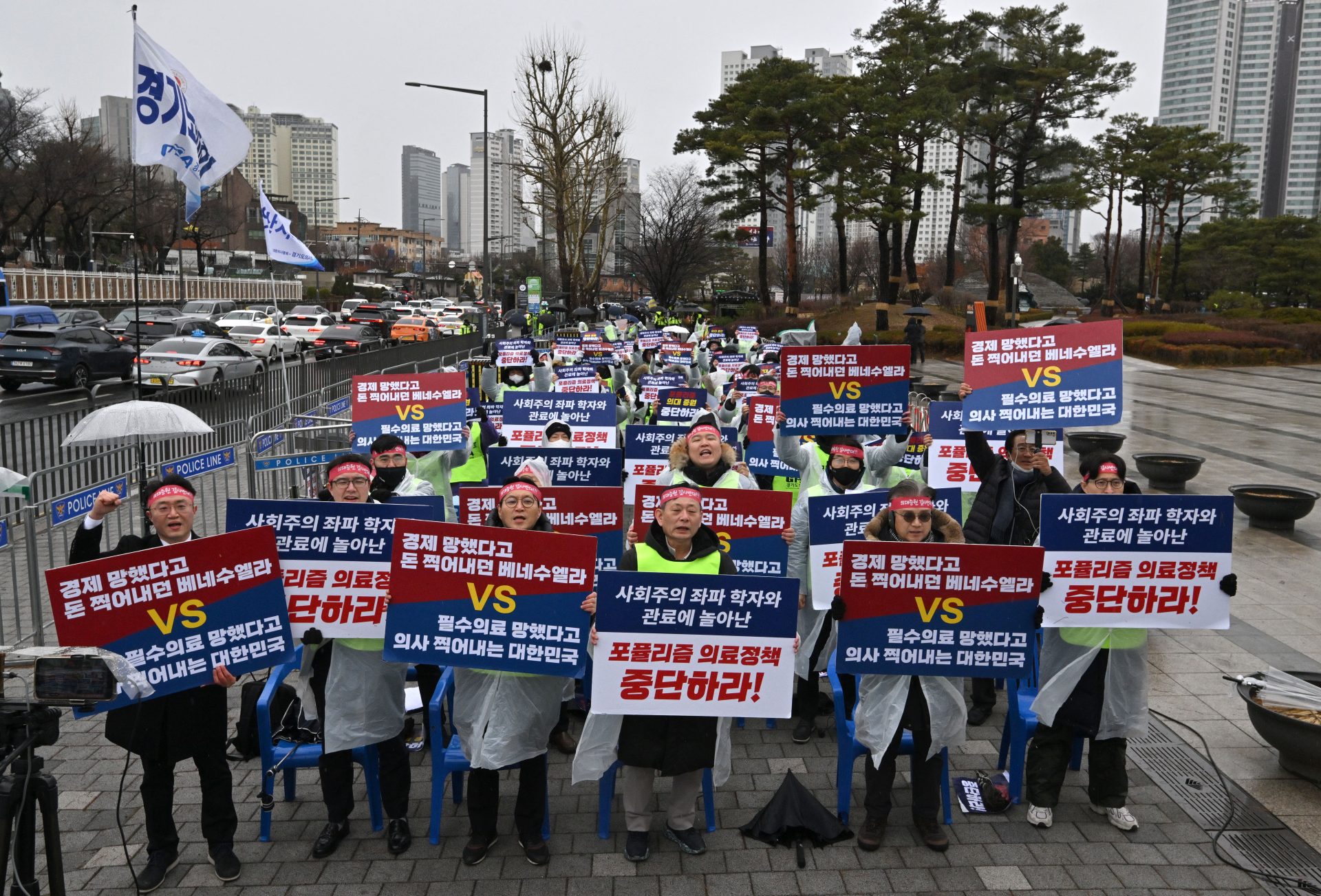 Doctors hold placards reading “Stop populist medical policy!” during a rally to protest against the government’s plan to raise the annual enrollment quota at medical schools, near the presidential office in Seoul on Feb. 21, 2024. Pregnant women had C-sections canceled and cancer treatments were postponed on Feb. 21, as the number of South Korean trainee doctors to walk off the job over proposed reforms swelled, officials and local reports said.
