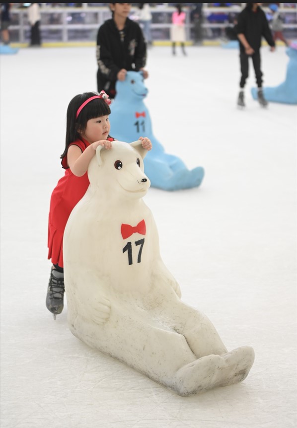 A young girl learns to skate with the assistance of a polar bear skating aid at SM Skating Megamall.