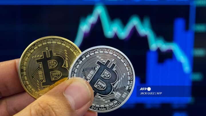 (FILES) A picture taken on 6 February 2018 shows a person holding a visual representation of the digital crypto-currency Bitcoin, at the "Bitcoin Change" shop in the Israeli city of Tel Aviv.