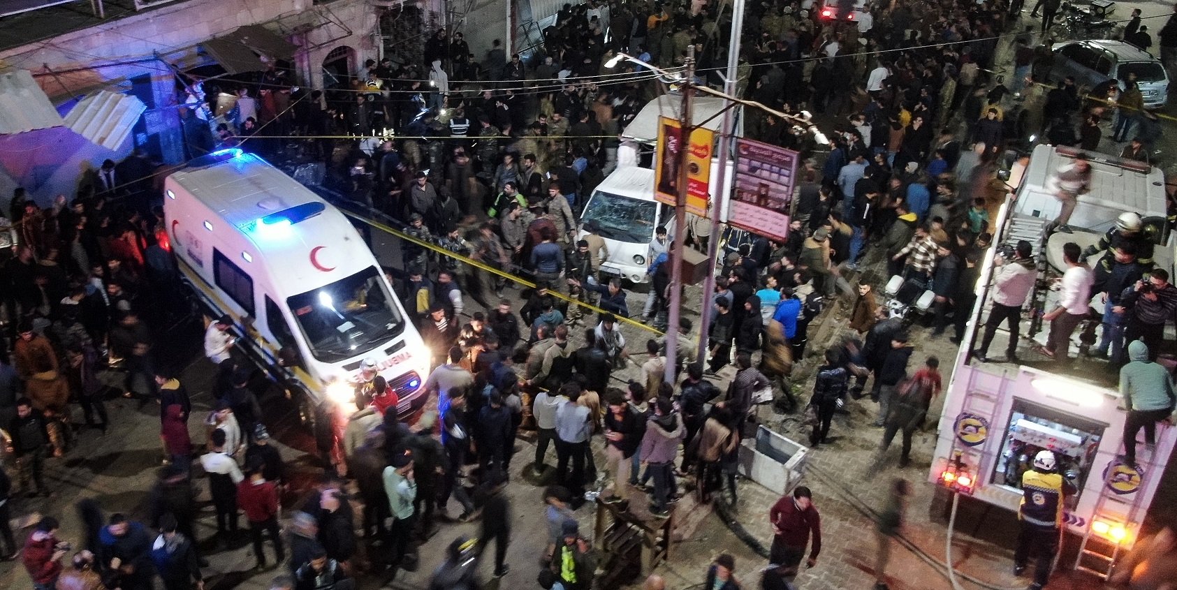 People gather around ambulances and a fire truck at the scene of a bomb explosion in the northern Syrian city of Azaz, early on 31 March 2024. The explosion took place in a market in the city held by pro-Turkish forces, killing at least eight people and wounding more than 20 others, a war monitor said.