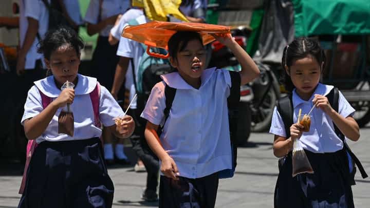 A student uses an envelop to protect herself from the sun during a hot day in Manila on 2 April 2024.