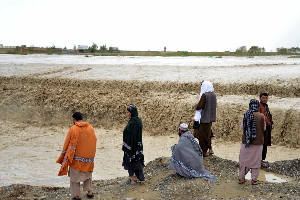 Afghan people wait to cross a flooded area in Spin Boldak district of Kandahar province on 13 April  2024, after a flash flood following a heavy rainfall.