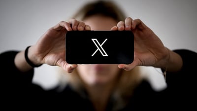 Tribune-woman-holding-smartphone-showing-x-logo