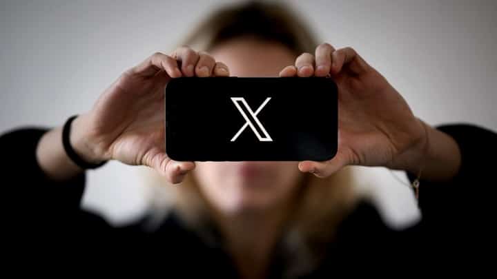 Tribune-woman-holding-smartphone-showing-x-logo