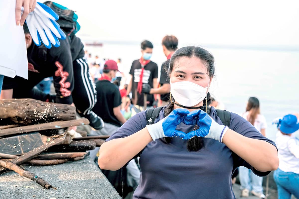 A woman gestures heart sign while collecting washed-up trash along the coast of Manila Bay during an event last year.