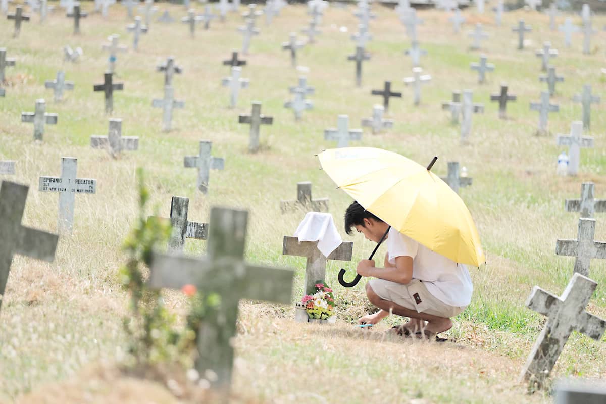 Kenneth Mendoza, a proud grandchild of late World War II veteran, Master Sgt. Homer Mendoza cleans the resting place of his grandfather