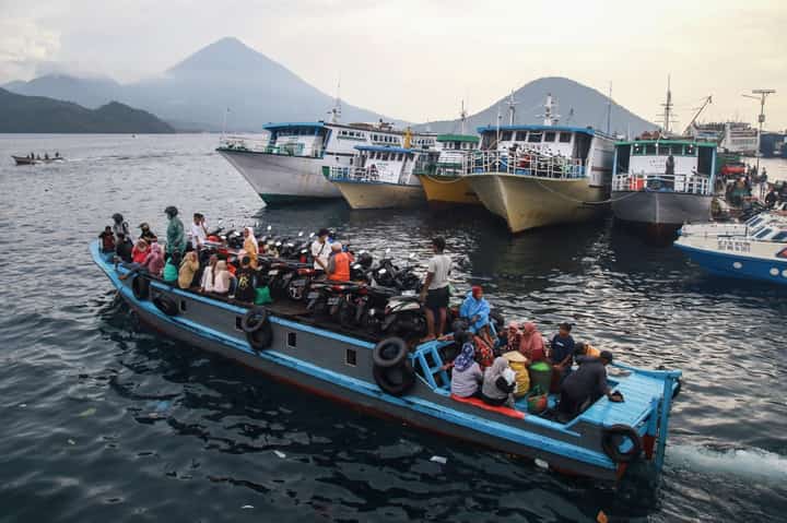 People travel on a wooden boat with motor scooters to Tidore Island ahead of Eid al-Fitr, which marks the end of the Muslim fasting month of Ramadan, at Bastiong port in Ternate, North Maluku, on 7 April 2024.