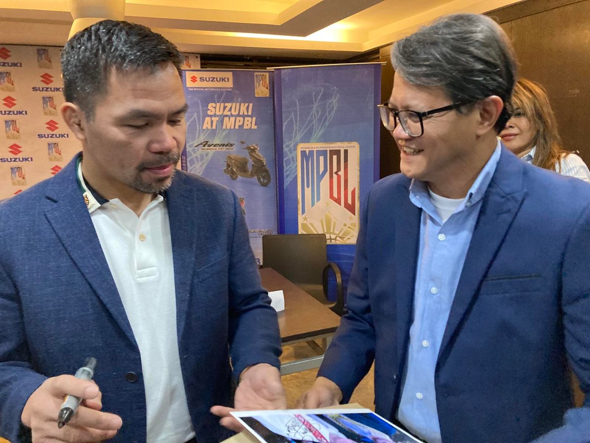 Boxing star Manny Pacquiao signs an autograph of his photo with former WBC flyweight champion Erbito Salavarria, whose son Jose Salavarria (right) is the chief of Suzuki Philippines’ motorcycle division during the contract signing between the MPBL and the Japanese company.