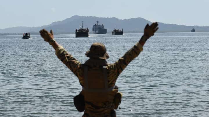 Navy man signals to Philippine landing ships loaded with Philippine-US marines