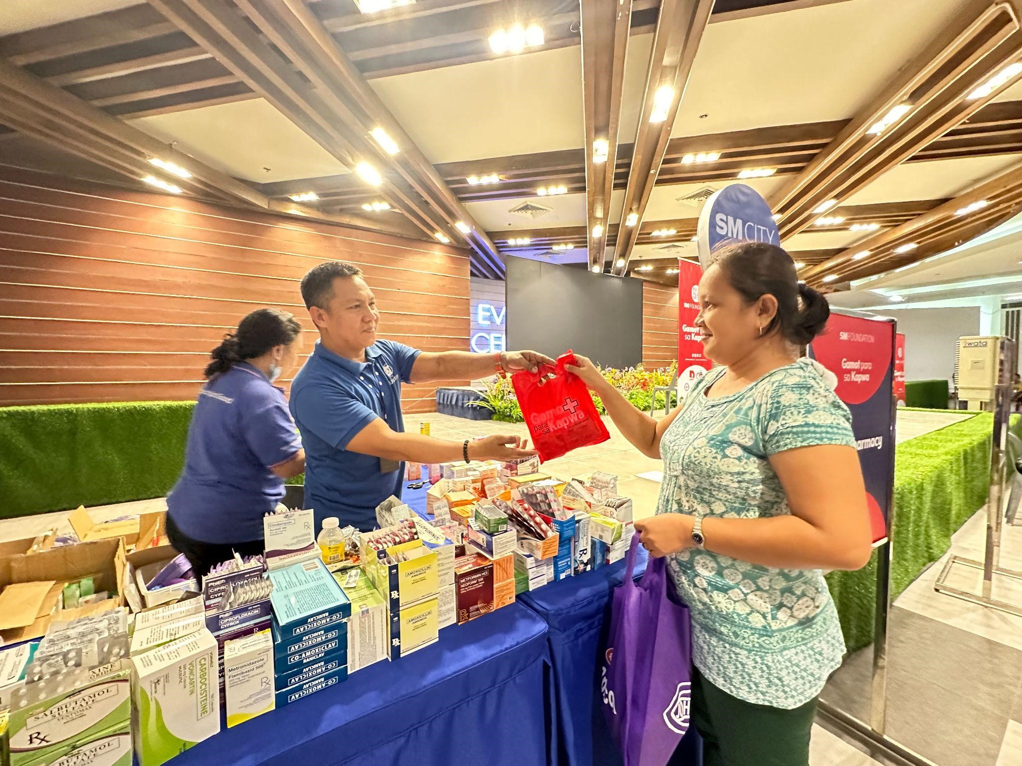 SM Foundation staff hands over free medicines to Loida.