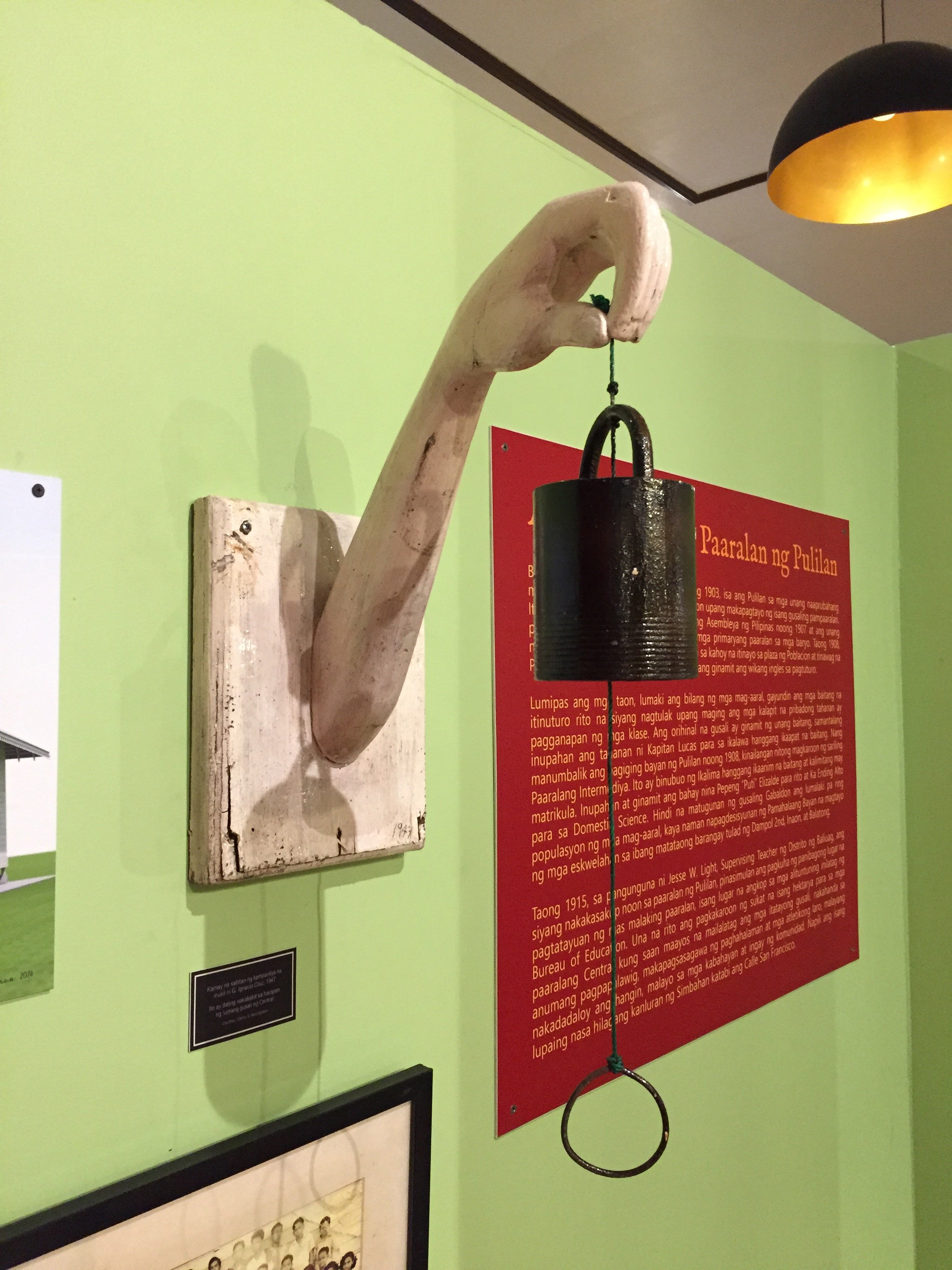Carved bell holder in the shape of an arm.