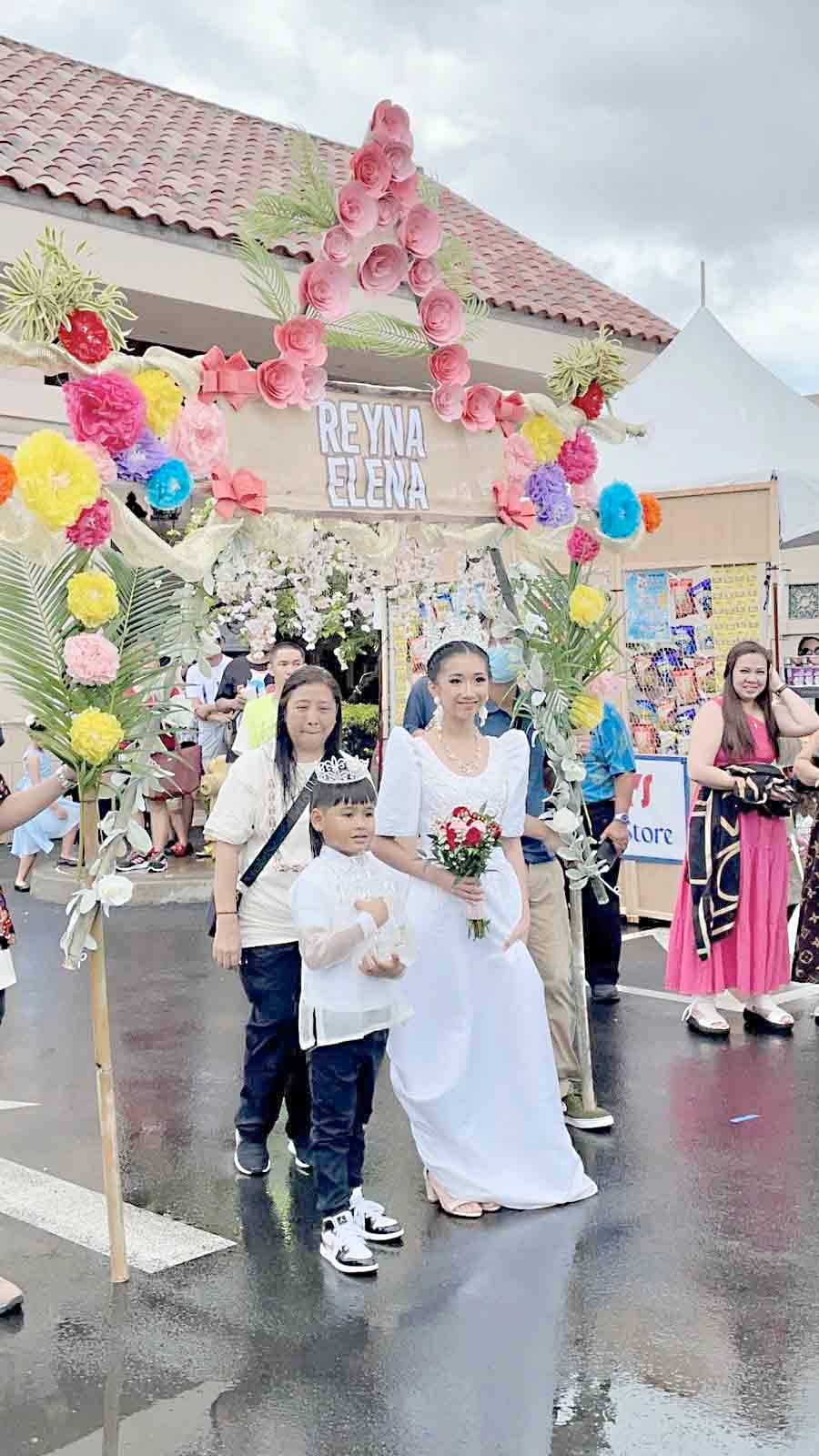 Donning in a white dress, the Santacruzan’s Reyna Elena was escorted by a little boy who also wore a crown.