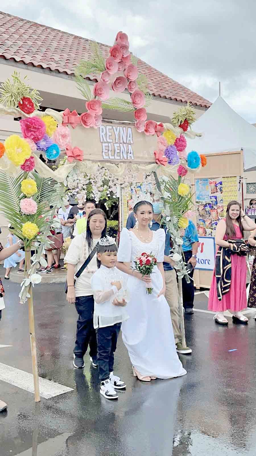 Donning in a white dress, the Santacruzan’s Reyna Elena was escorted by a little boy who also wore a crown.