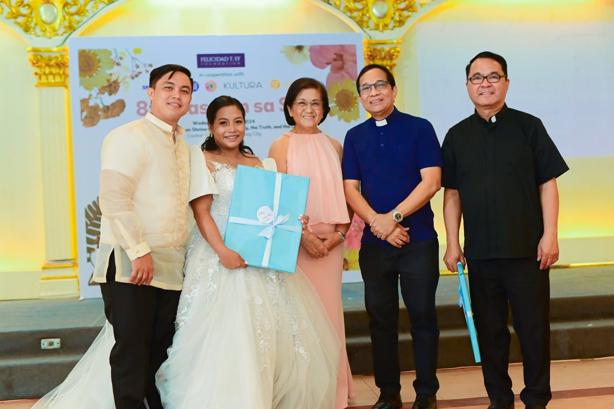 A wedding gift, presented on behalf of SM Group matriarch Felicidad Sy, is given to all the 16 couples. In the photo, Paulo (left) and Sherry Joy Amita (second from left) receive theirs from the Felicidad T. Sy Foundation, Inc. (FTSFI) Executive Director Mel Elido (center), Reverend Father Rey Reyes (second from right), and Shrine Rector Reverend Father Danny Canceran (right).