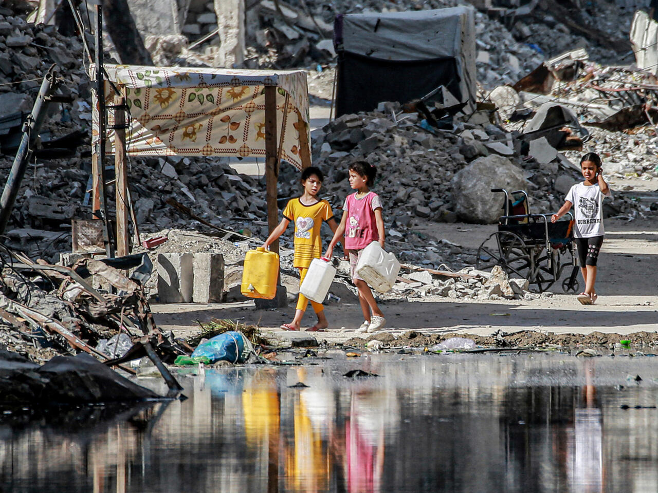 Palestinian girls walk past a lake of sewage leaking from collapsed underground pipes in Gaza's second city of Khan Yunis