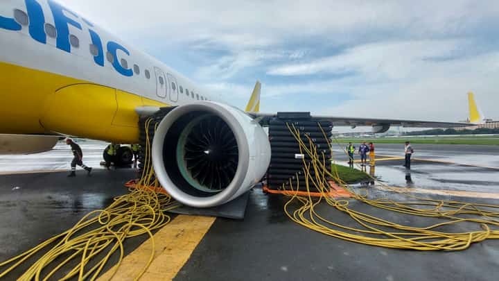 Workers from Cebu Pacific check on the aircraft that was lodged on a soft part along the runway at Ninoy Aquino International Airport Terminal 3 on Friday while being moved from a bay.