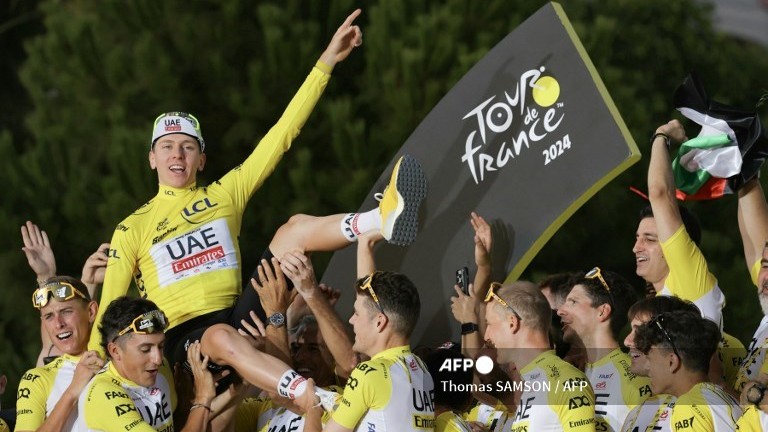 UAE Team Emirates team's Slovenian rider Tadej Pogacar celebrates his overall victory on the podium with teammates and staff after the 21st and final stage of the 111th edition of the Tour de France cycling race, a 33,7 km individual time-trial between Monaco and Nice, on July 21, 2024.