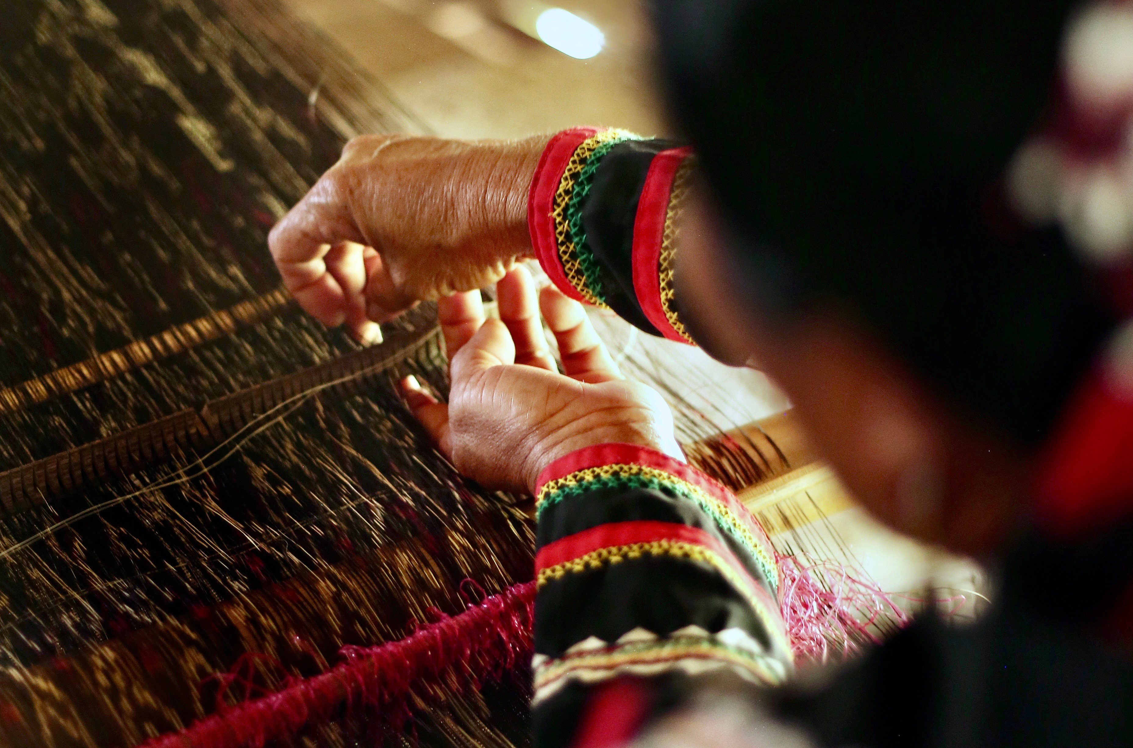 The deft hands of a weaver over a loom.
