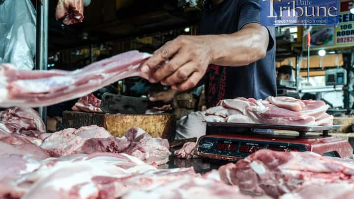 A meat vendor chops a pork belly upon order on Sunday. The Bureau of Animal Industry (BAI) has intercepted several trucks carrying pigs from African Swine Fever-hit areas, and the Department of Agriculture suspects that these traders are a major source of the virus's spread.