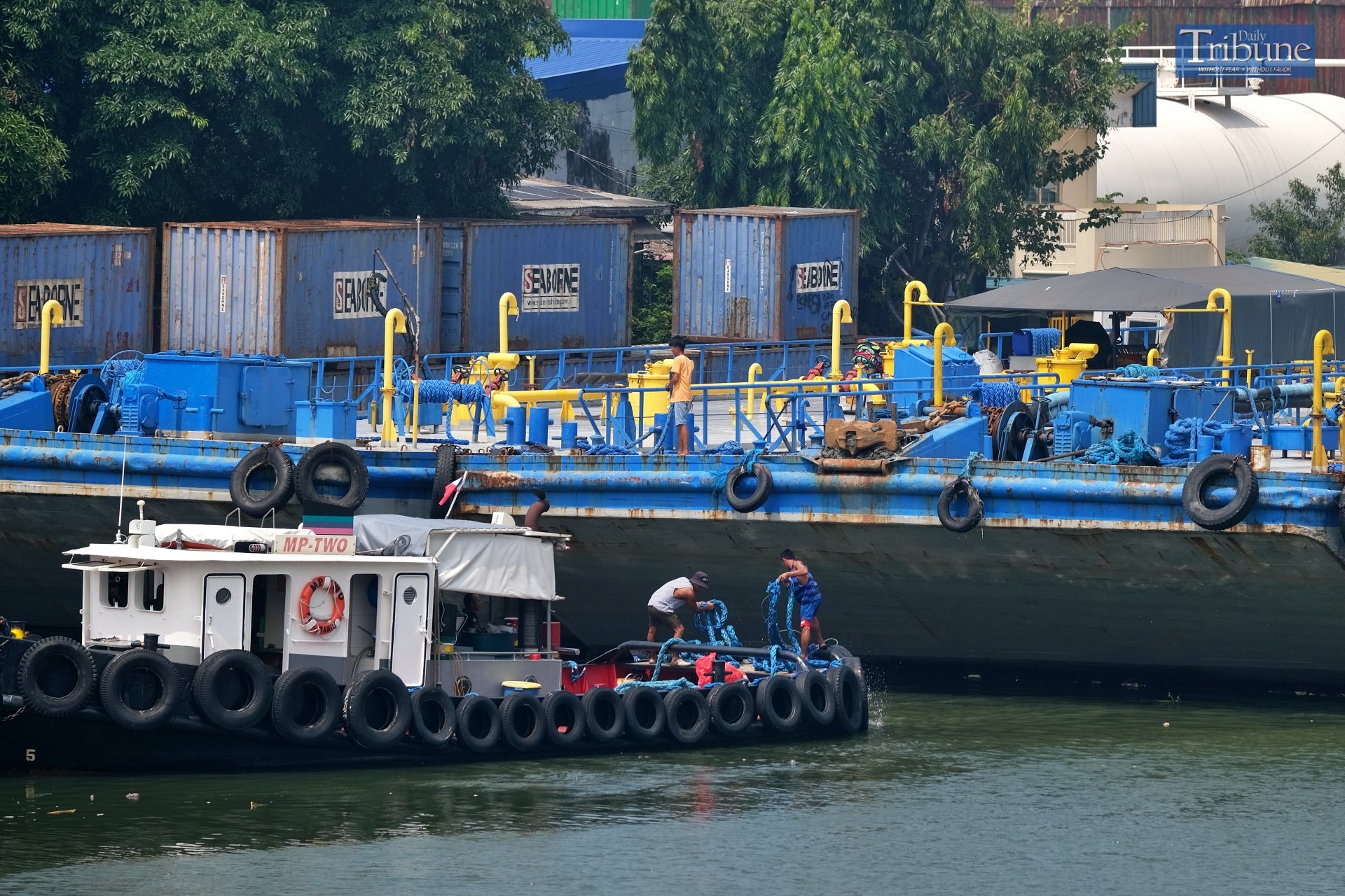 Tugboat personnel loosen the tie from their boat to the huge barge after they successfully manage to properly park the barge on a section of the Baseco Compound in Manila on Tuesday.