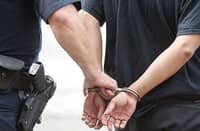 A police officer handcuffing a suspect during an arrest, a representative image for buy-bust operations or law enforcement actions.