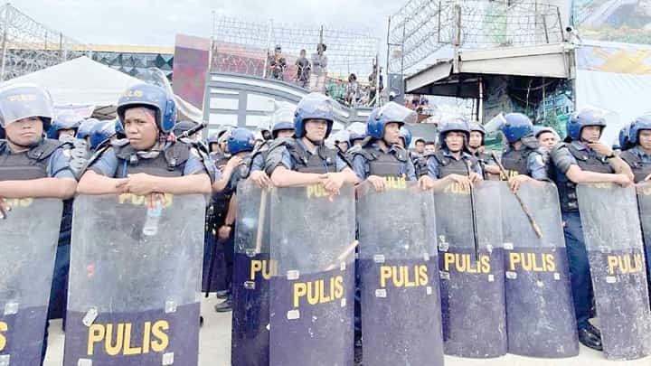 Anti-riot officers start barricading the main gate of the Kingdom of Jesus Christ compound in Davao City on Saturday, 24 August, as they serve the no-bail arrest warrant of its leader Pastor Apollo Quiboloy and his co-accused.
