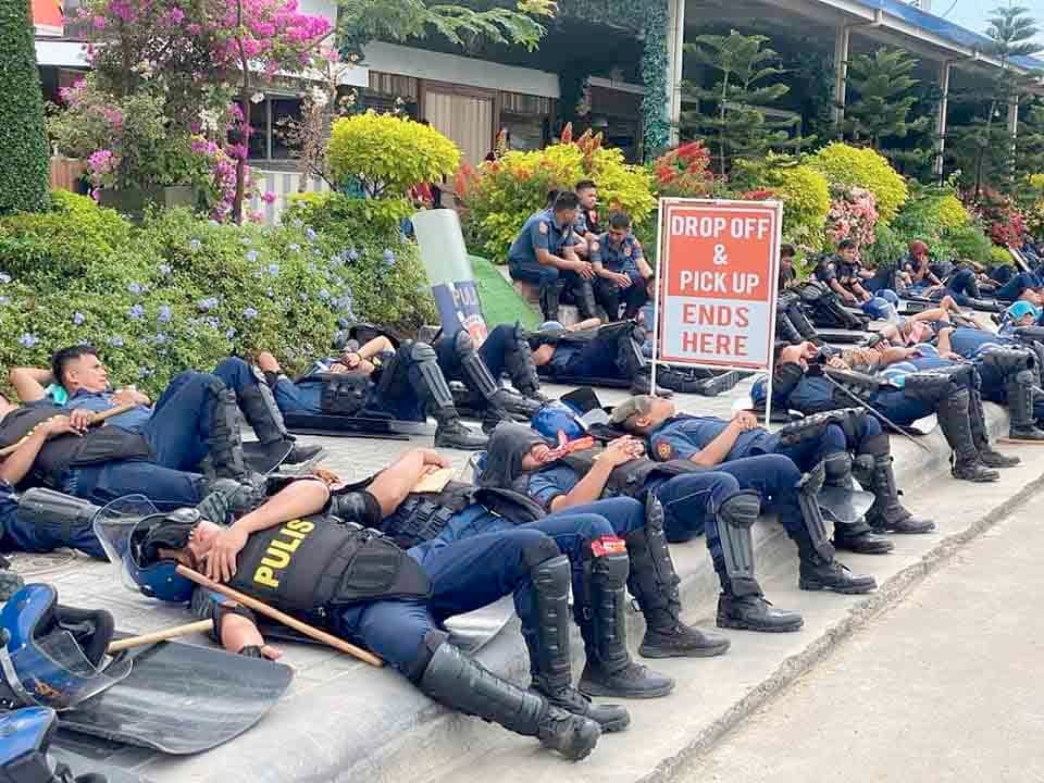 Anti-riot officers wait by the main gate of the Kingdom of Jesus Christ compound in Davao City on Saturday, 24 August, as they serve the no-bail arrest warrant of its leader Pastor Apollo Quiboloy and his co-accused.