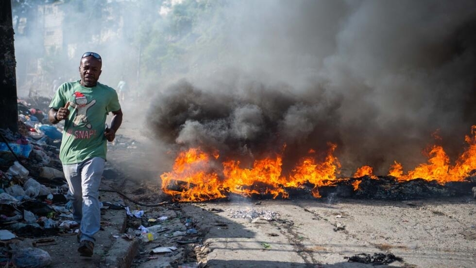 People walk past burning tires, during a demonstration against insecurity in Port-au-Prince, Haiti