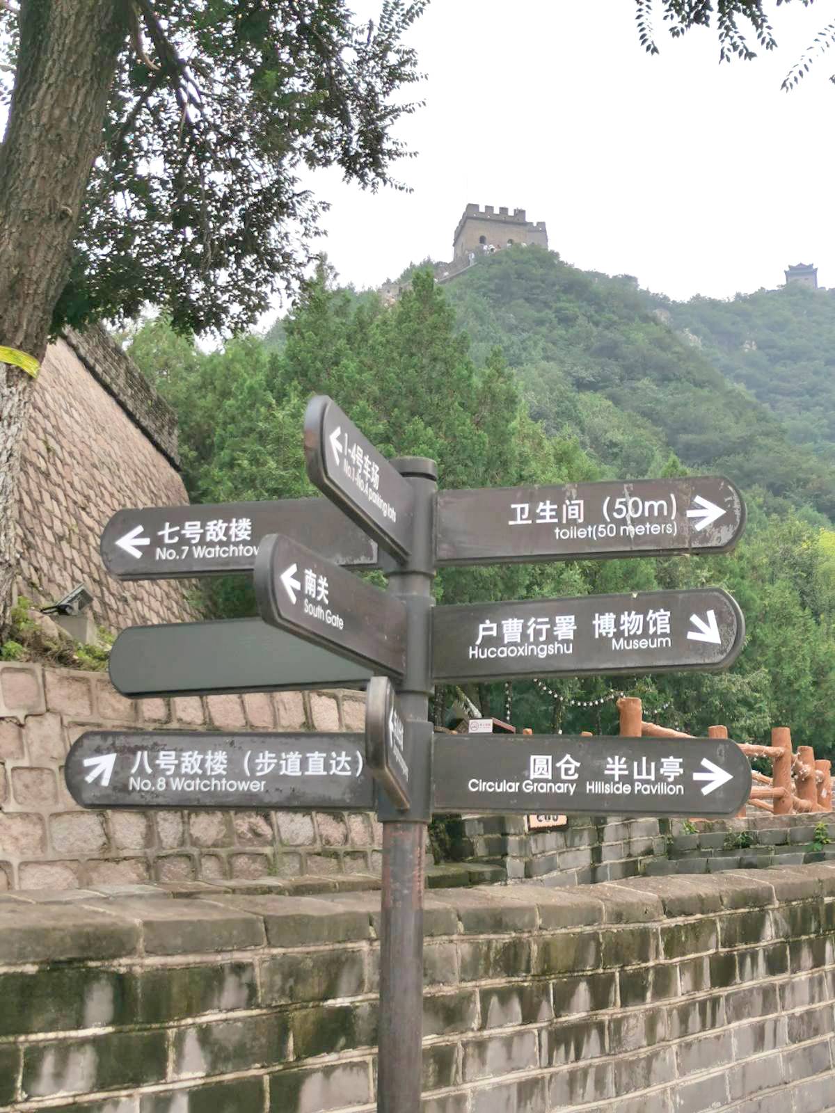Brown signs guide visitors to specific areas within the Juyongguan section of the Great Wall.