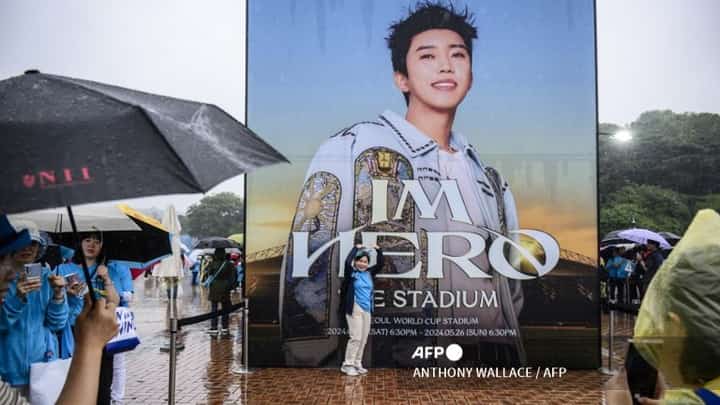 (FILES) This photo taken on 26 May 2024 shows a fan posing for photos with a poster of trot singer Lim Young-woong before attending his 'IM HERO - THE STADIUM' concert at the Seoul World Cup Stadium in Seoul. Lim Young-woong may not have as many fans as BTS, but the trot singer is rivaling the global superstars, showing there's more to South Korean music than K-pop with his billions of streams and a sold-out stadium tour.