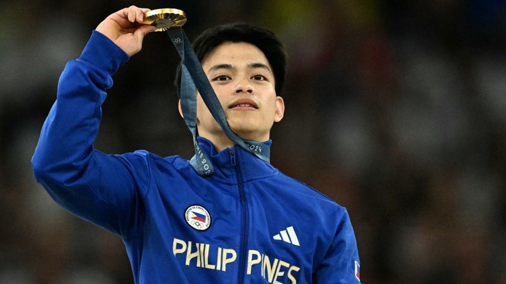 Carlos Yulo proudly shows off the gold medal after winning the floor exercise in the Paris Olympics.