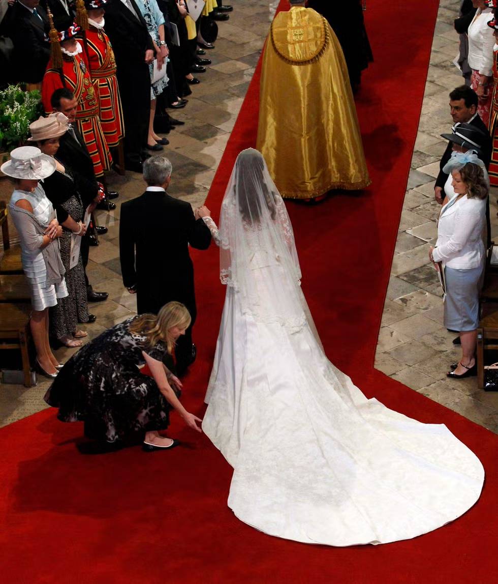 Burton adjusts Kate Middleton’s gown as she arrives with her father Michael Middleton at Westminster Abbey for her wedding.
