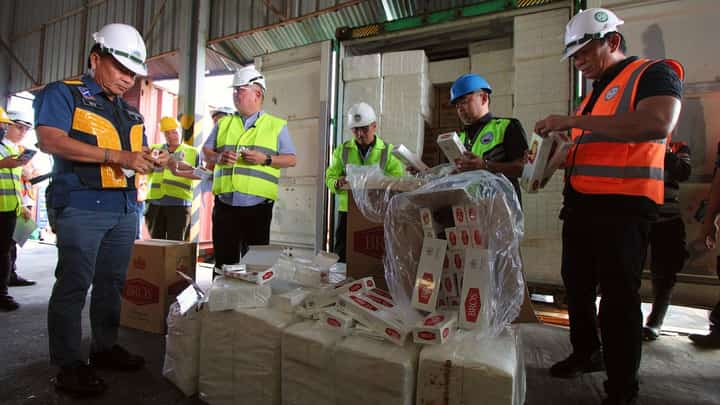 Agriculture Secretary Francisco Tiu Laurel and BOC Port of Subic Atty. Ricardo Uy Morales II inspect the smuggled contraband presented to the media on Wednesday at the New Container Terminal. The P136 million of smuggled items that were found inside seven container vans include fake cigarettes and vegetables that came from Taiwan and China, respectively.