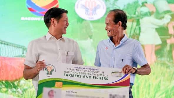 PRESIDENT Ferdinand Marcos Jr. (left) hands a mock Agri-Puhunan at Pantawid Program ID to a beneficiary farmer during the launching of the APPP at the Our Lady of Sacred Heart Gymnasium in Guimba, Nueva Ecija.