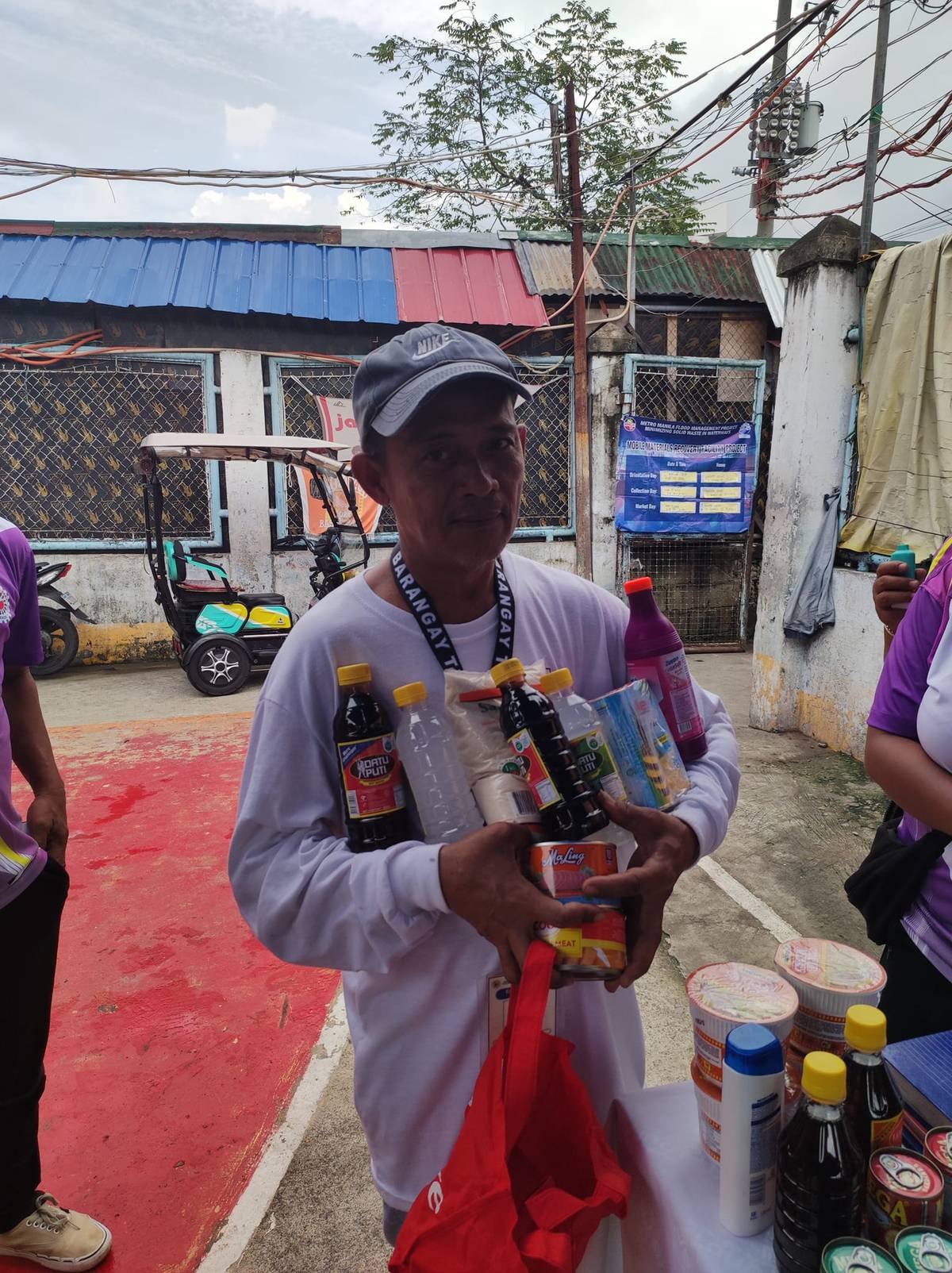 RESIDENT of Barangay Tejeros shows groceries he got in exchange for recyclable PET bottles he collected at the Recyclable Palit Grocery booth in the village on 17 September.