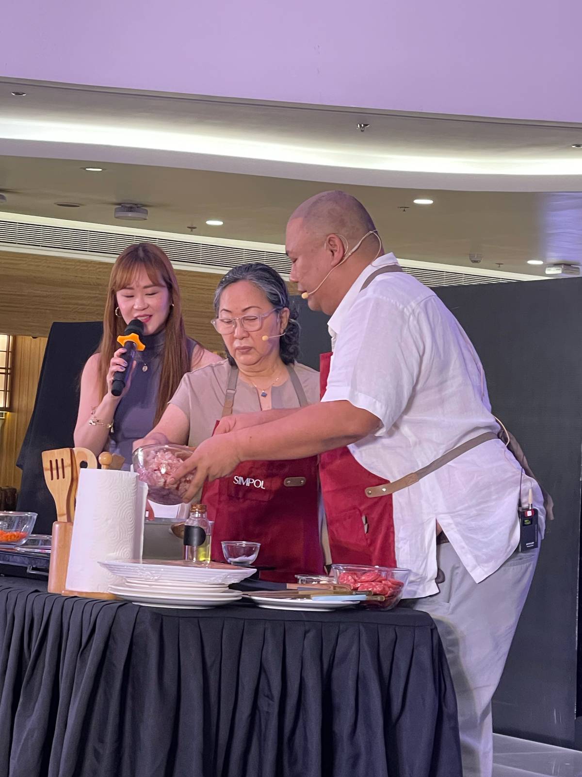 Chef Tatung cooking with a lucky member of the audience, Menchie Porcincula, as host Jill Ngo looks on.