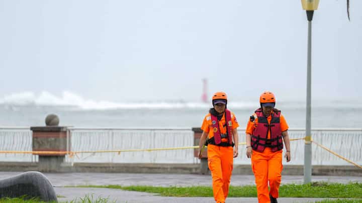 Waves break off Sizihwan Bay beauty spot in Kaohsiung as coast guard officers patrol ahead of the arrival of Super Typhoon Krathon