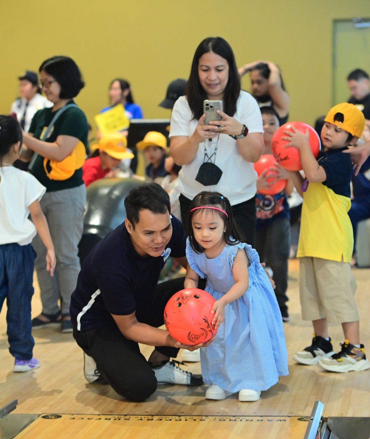 A child of an SM Prime employee rolls a bowling ball at the SM Bowling Center during the SM Prime Kids event, promoting family bonding.