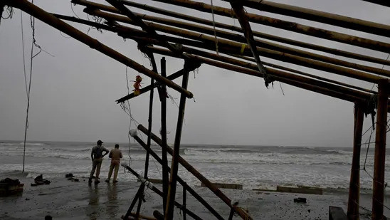 Police personnel stand guard ashore near a damaged shop at a beach in Balasore on 24 October 24, hours before cyclone Dana hit the coasts of Odisha and West Bengal.