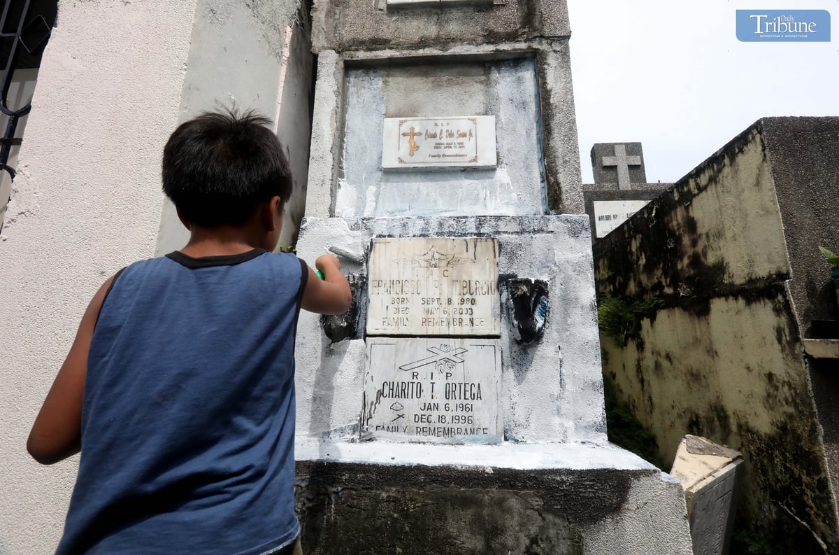 A young boy repaints the tomb of his departed grandmother and uncle at San Juan City Cemetery on Monday, October 28, 2024, in preparation for All Souls' Day.