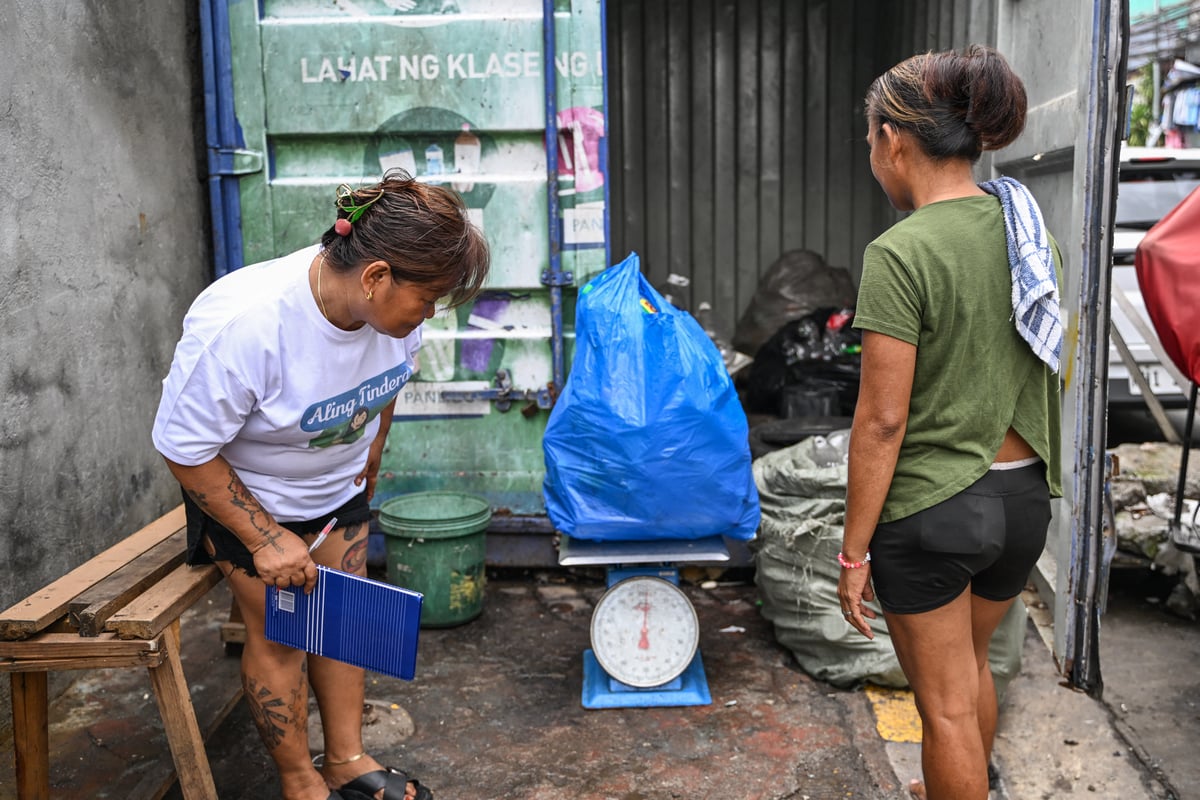 Marita Blanco (left), checks the weight of plastic waste sold to her before reselling it to United States charity organization Friends of Hope in its waste-to-cash program, in Manila.