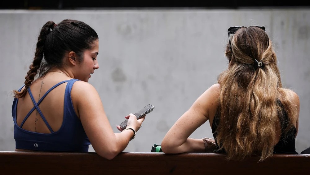 Two women looking at their phones in Sydney, Australia, on Thursday.