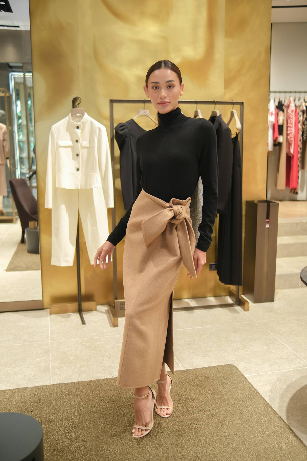 A black cashmere turtleneck is paired with a camel wool skirt with a knot detail.